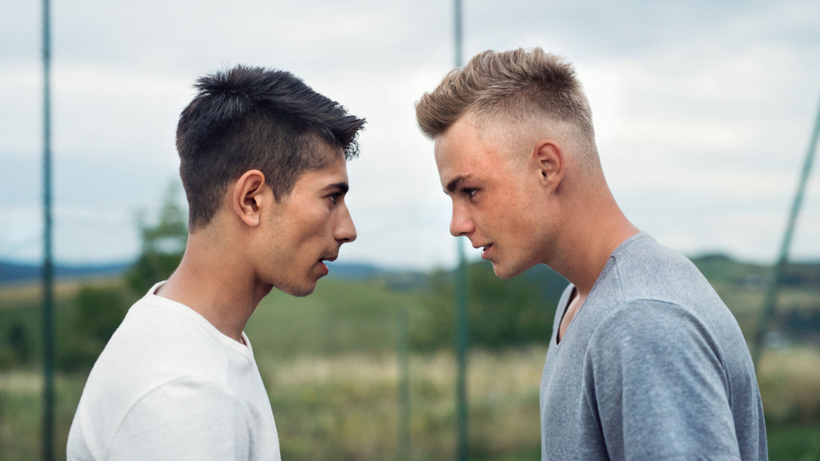 Two teenage boys outdoors on playground looking at each other 