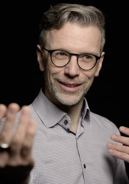 A man with beard and glasses (Titus Neupert) gesticulates while speaking